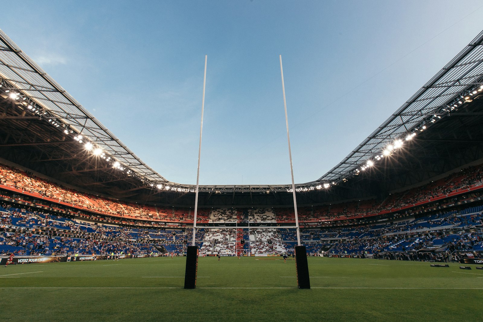 Rugby goal posts on a green pitch inside a large crowded stadium in France