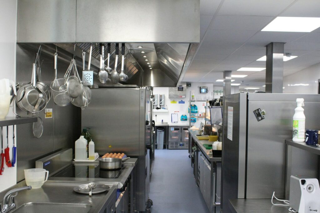 Commercial kitchen with stainless steel worktops, an extraction canopy and an induction hob station