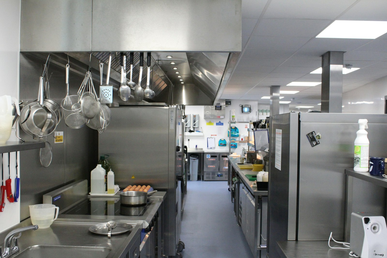 Commercial kitchen with stainless steel worktops, an extraction canopy and an induction hob station