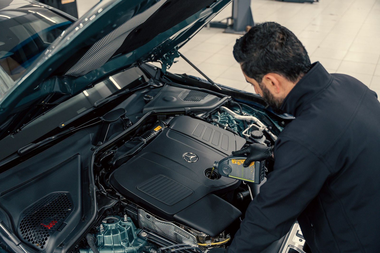 Mechanic inspecting a car engine with the bonnet open, checking for faults such as steering problems