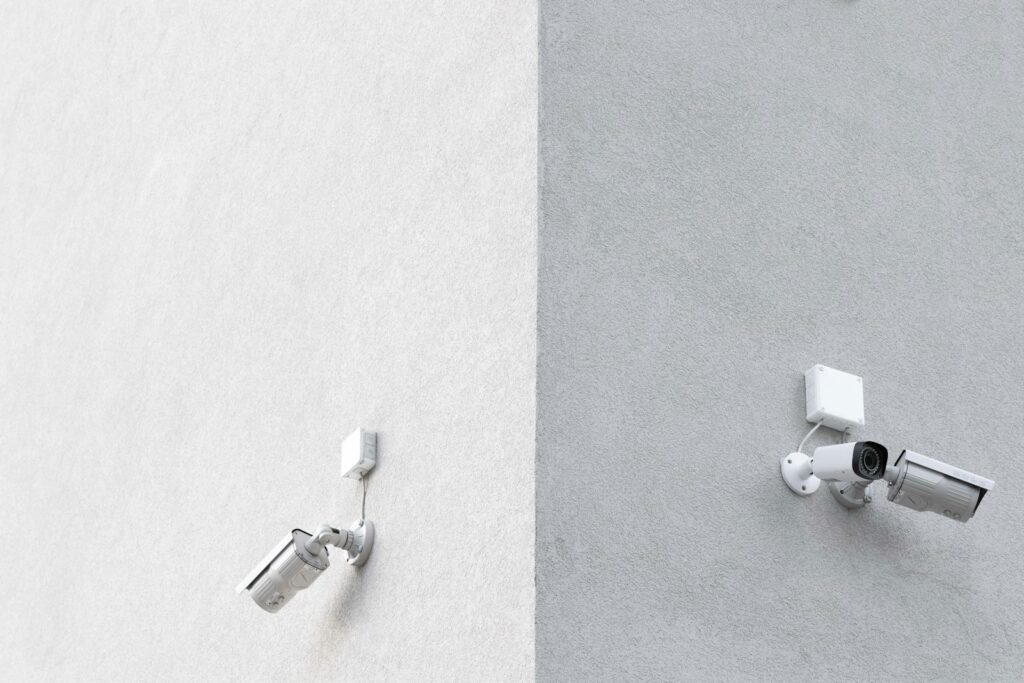 Three white CCTV cameras mounted on a building wall, showing common outdoor security camera placement