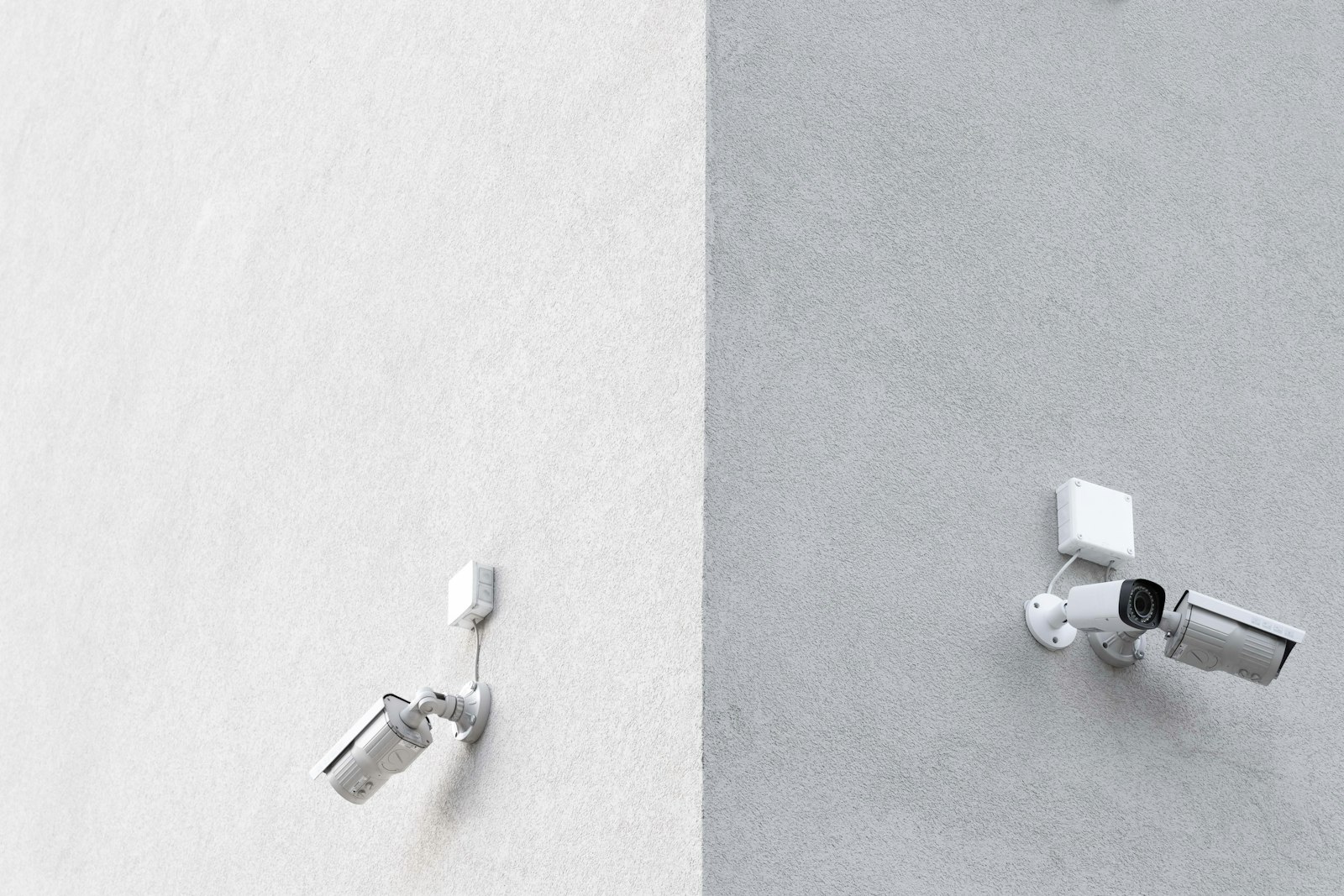 Three white CCTV cameras mounted on a building wall, showing common outdoor security camera placement