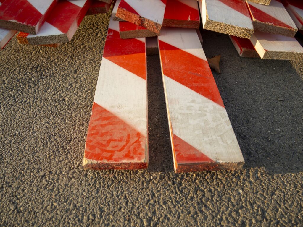 Red and white striped construction barriers stacked together, similar to high-visibility roadworks markings
