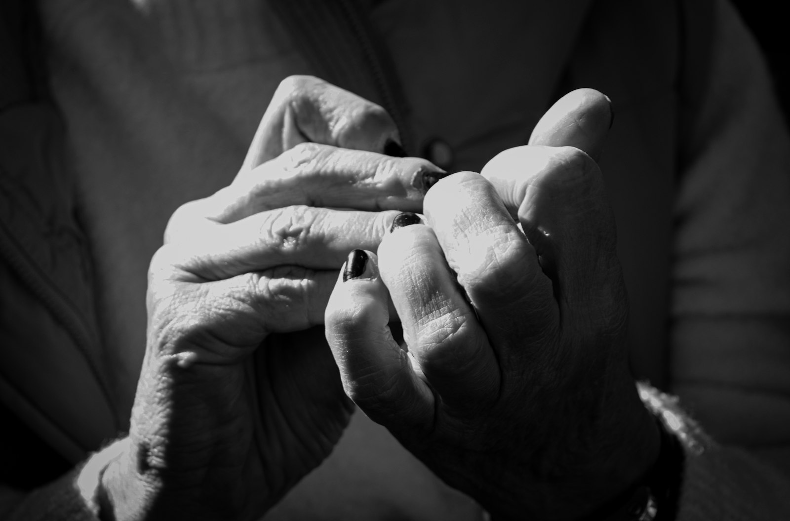 Close-up of two hands holding each other, suggesting comfort and support for an elderly relative