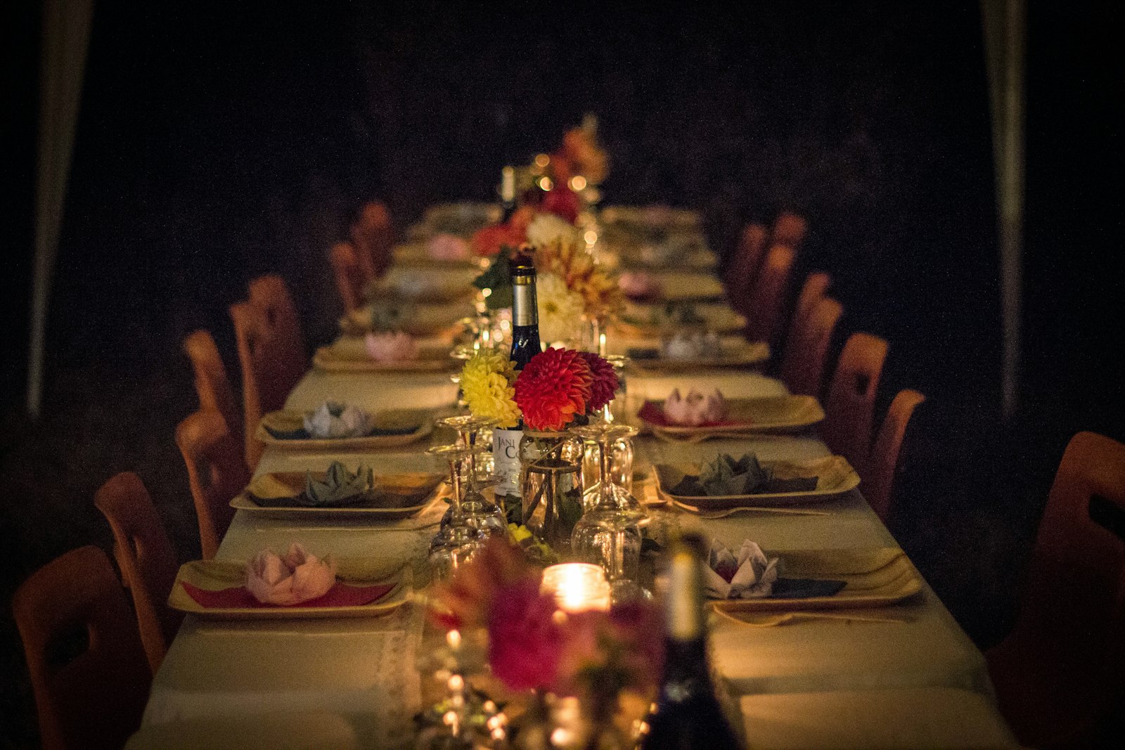Long dining table set for a dinner party with flowers and candles, ready for guests