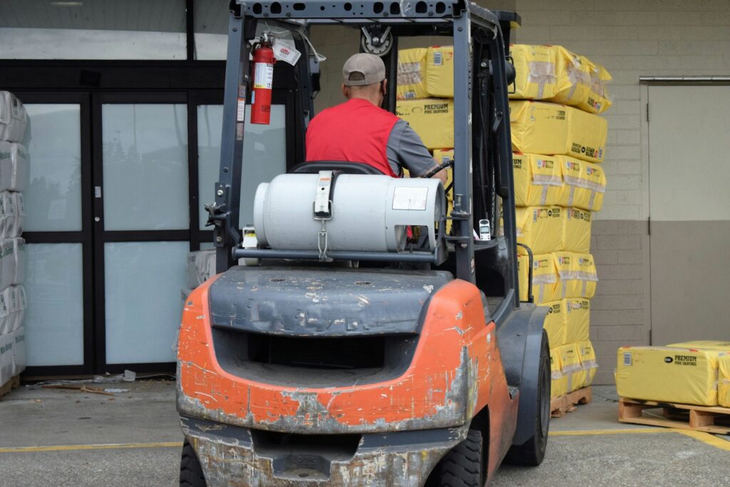 Man driving a forklift in a warehouse, showing the machinery operators are trained to use